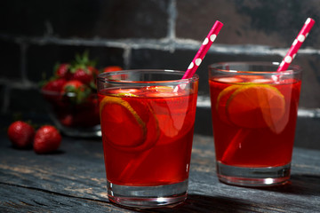 two glasses of strawberry lime lemonade on a dark wooden background, closeup