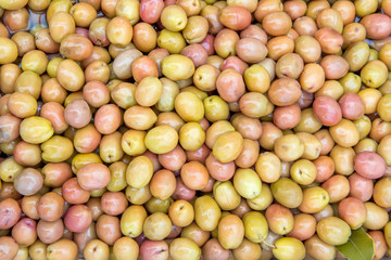 Background of green and pink olives in pickle, sold on the market