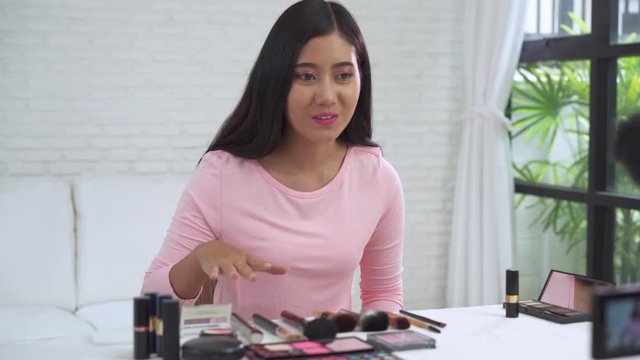 Beauty blogger present beauty cosmetics while sitting in front camera for recording video. Beautiful woman use brush while review make up tutorial broadcast live video to social network by internet.