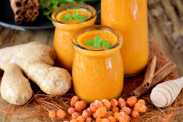 Yellow smoothie with berries of sea buckthorn in glass jars decorated with mint