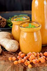 Yellow smoothie with berries of sea buckthorn in glass jars decorated with mint