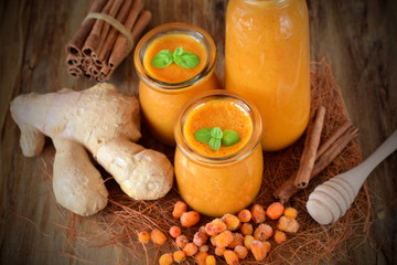 Yellow smoothie with berries of sea buckthorn in glass jars decorated with mint