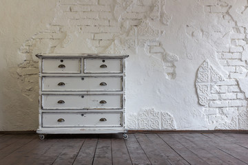 Vintage chest of drawers in the background of the old wall. Vintage interior.