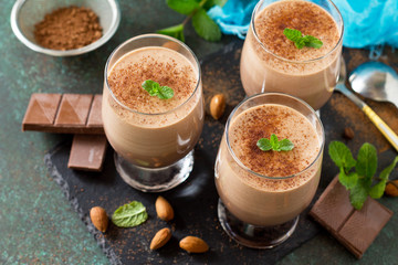 Chocolate-nut mousse with mint in portion glasses on a stone or slate background.