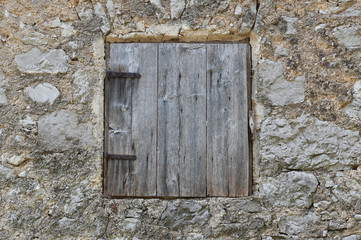 Fototapeta na wymiar Old and closed wooden window on a house made out of stone. Vintage window.