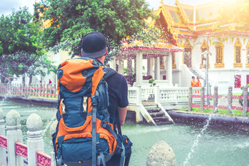 Backpacker man watching monks in a beautiful buddhist temple in Thailand