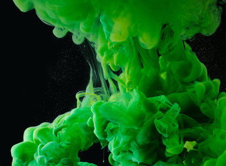 close-up view of green abstract flowing paint on black background
