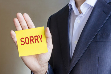 Businessman holding card with Sorry message