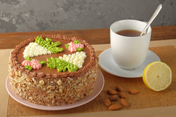 Homemade Kiev cake, cup of tea and scattered almonds on textile napkin on the wooden table. The known ukrainian delicacy. Close-up view.
