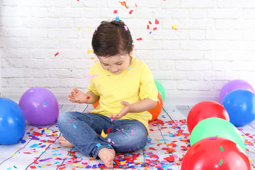 niño feliz lanzando confetti de colores rodeado de globos