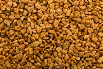 fragrant grains of fenugreek on a rustic background
