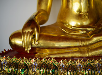 Fototapeta na wymiar Close up view of the low hand golden buddha statue sitting meditation with copy space and sunlight