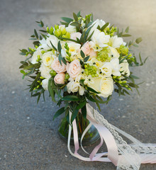 White Wedding Bouquet Roses Pink flowers and Ruscus Leaves with Robbons on Gray Asphalt Background. Wedding Decoration. Square Image.