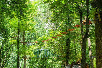 Rope Park among the trees. Walking on hanging stairs in a helmet. Children's rides on trees.