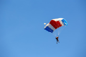 isolated skydiver  control colorful parachute gliding after free fall jump with blue sky background