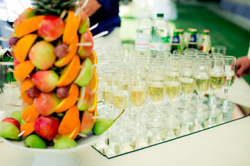 Fruit on the buffet table and glasses with champagne on the table fruit sliced dish apples oranges pears grapes