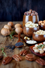 Different nuts and seeds in wooden spoons and bowls