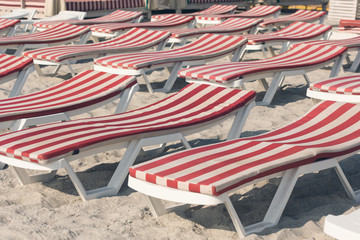 many chaise lounges with mattresses with red stripes stand on the sand on the beach, the concept of travel