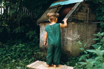 a boy with white hair in a green combination played at a well