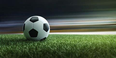 Fußball liegt auf Stadionrasen vor Lichteffekten