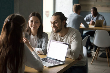 Smiling couple meeting realtor or mortgage insurance broker in cafe, financial consultant making offer to happy clients with laptop in public place, millennial friends having fun in coffee shop
