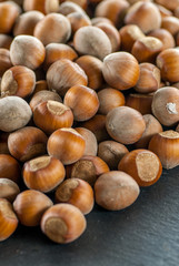 close up photo of a pile of raw hazelnuts on a slate