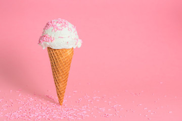 funny creative concept of wafer cone with ice cream covered and strewed sprinkles on pink background, copy space