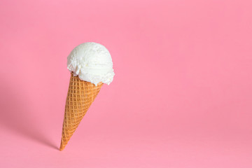 creative concept of close up falling single wafer cone with ice cream on pink background, copy space