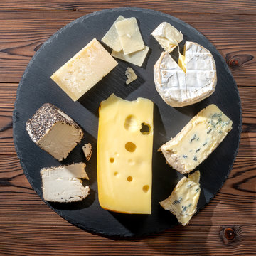 top view of tasty various types of cheese on slate stone background