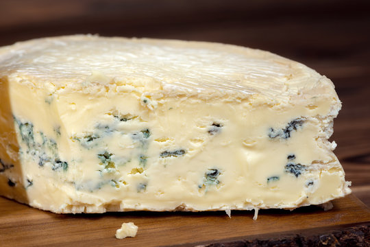 tasty whole blue cheese with mold on wooden background, close up, Italian, French cheese