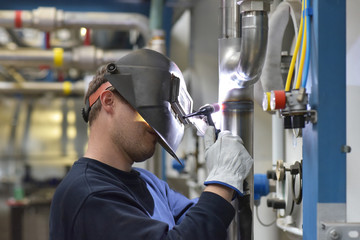 Schweißer repariert Rohrleitungen in einer Chemiefabrik // welder at work in reffinery