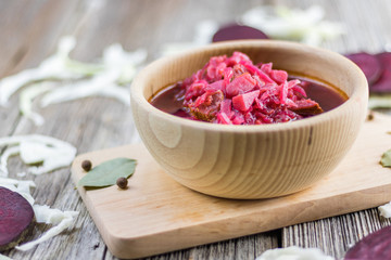 Detailed view on a Borscht soup from  beetroot and cabbage on a wooden board