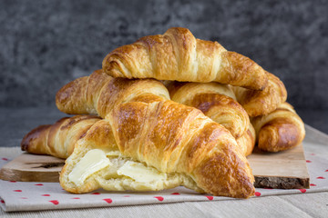 Gold butter croissant greased with butter on natural wood plank