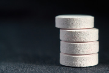 white pills on black textile background. medical pharmacy