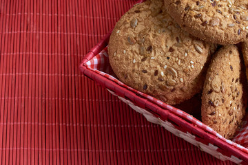 homemade oat cookies with sunflower seeds in and near red checkered basket on wooden table