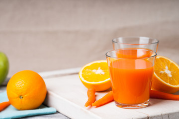 Glasses with carrot juice, apple and sliced orange