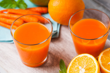 Glasses with carrot juice, apple, sliced orange and mint leaf 