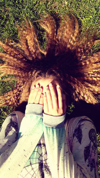 Сlose up of happy young woman lying on cereal field and covering face by hand
