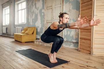 Male yoga doing balance exercise on mat in gym