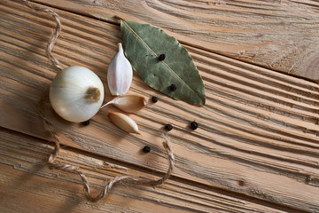 onion, garlic, black pepper and bay leaf on a wooden background