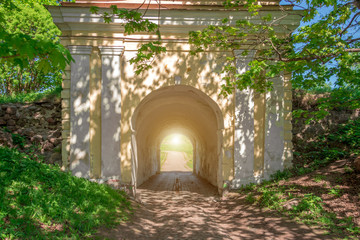 Architectural stone arch in the forest and light at the end of the tunnel.