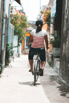 Girl doing bicycle in the old streets of Hoi An, Vietnam