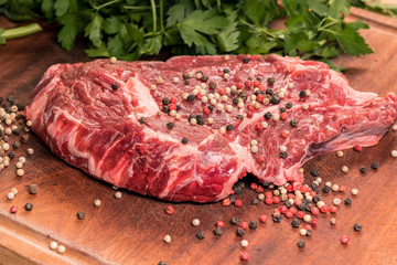 steak of beef on a wooden board with spices and parsley