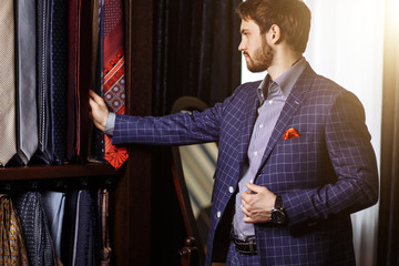 Elegant European Man choosing necktie or tie to match his suit in custome made garment fashion...