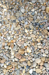 Closeup of rocks, pebbles and boulders on rocky beach which have been eroded smooth by the wave action of the water