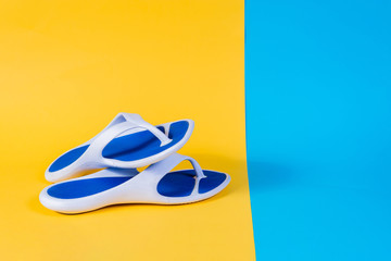 Blue Flip-flops, summer set. Summer is coming concept. Minimal style, minimalist photography. Yellow, pink and blue pastel colors background.