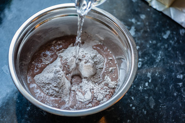 Process of preparation of cupcakes. Adding water to the dough. Close up, soft focus. Homemade cupcake.