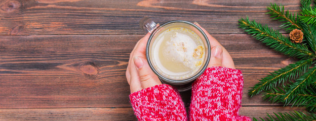 Cocoa with marshmallows in the hands of a wooden background
