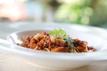 spaghetti Bolognese with minced beef and tomato sauce garnished with parmesan cheese and basil , Italian food