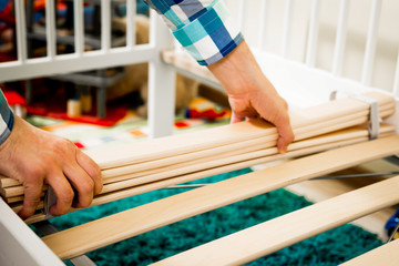 Construction of bed for children. The man puts the bed frame. Role of the father in child's life. Father folds bed for a newborn child, growing up children, Concept of parenthood.